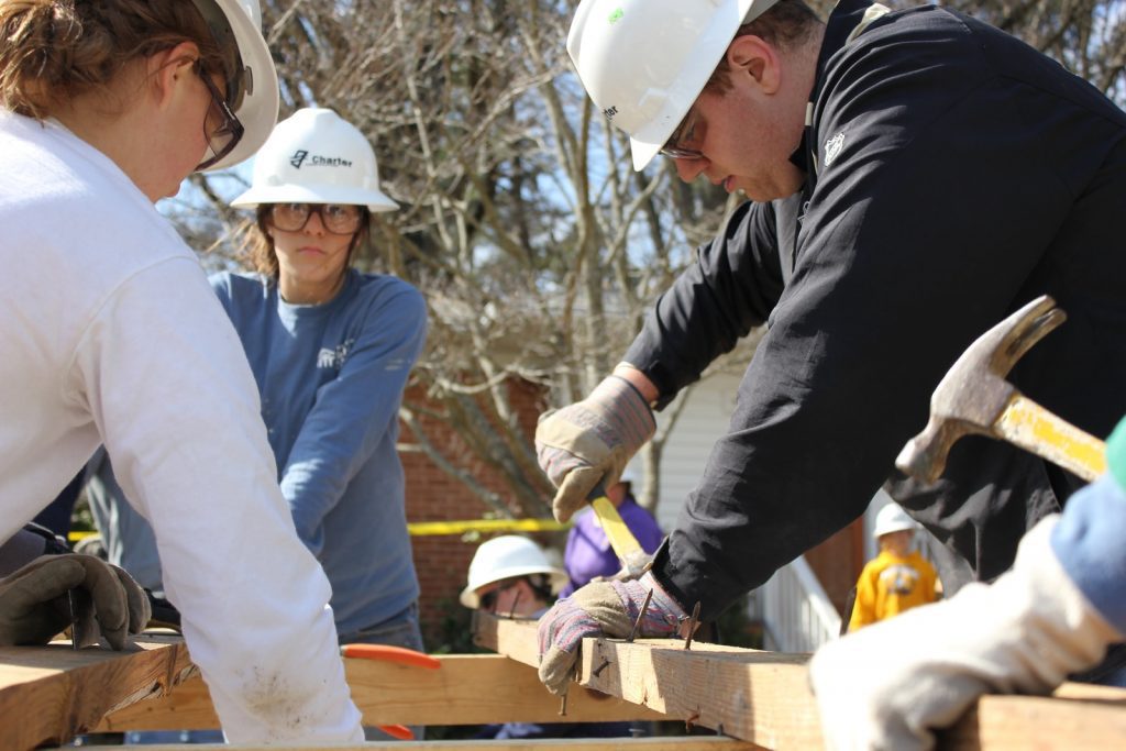 Photo by Brad Weaver man in black jacket and white hard hat holding green plastic bottle